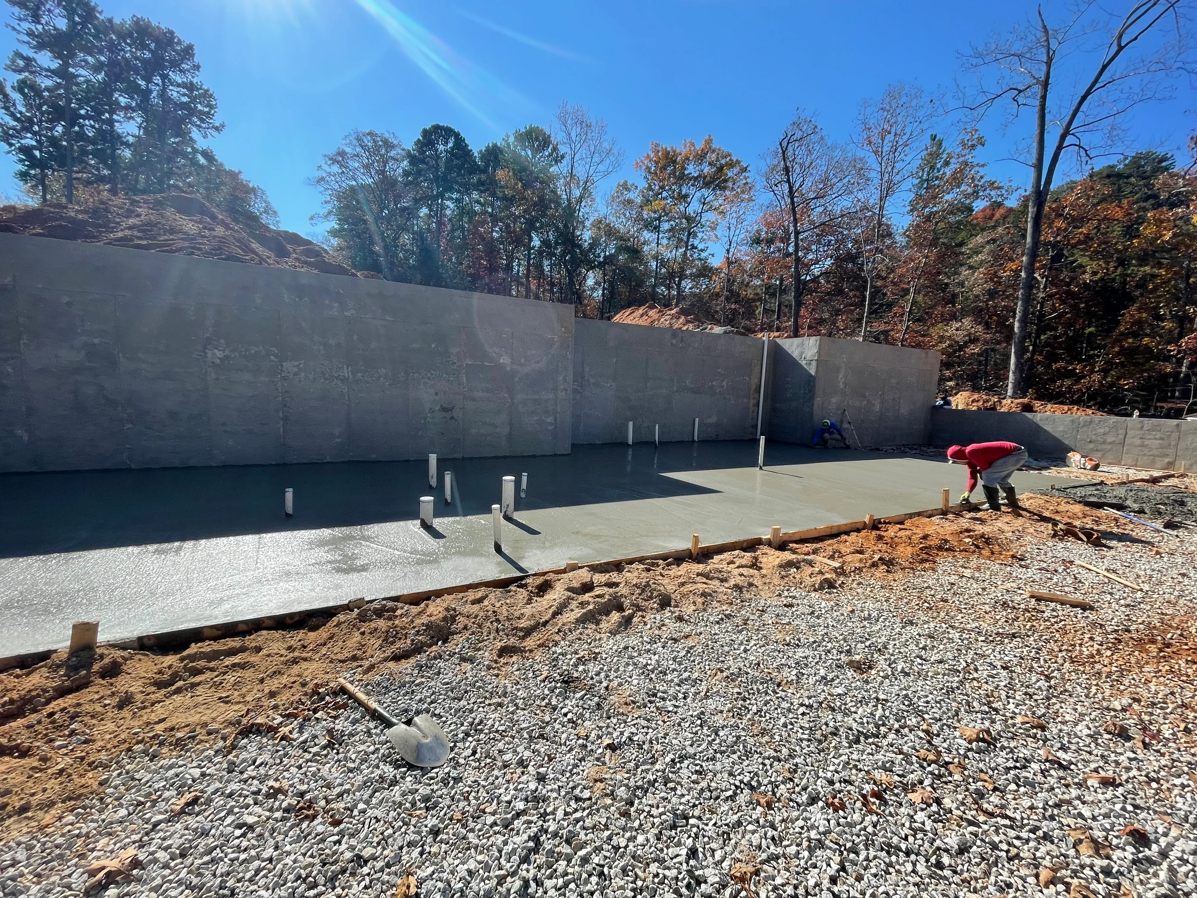 Concrete foundation slab with retaining walls and anchor posts on gravel base