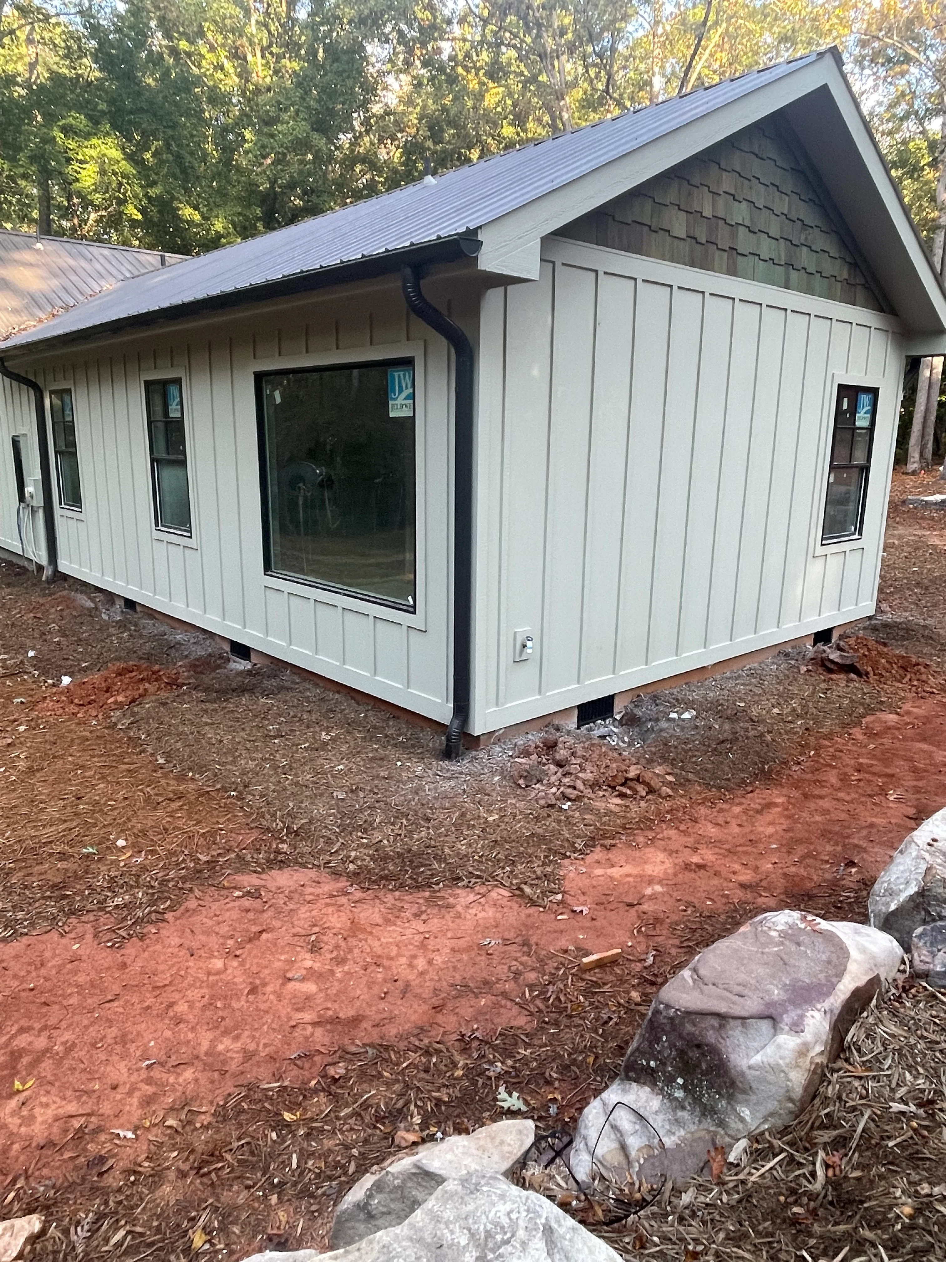 Standing seam metal roof and vertical siding on residential addition with large windows