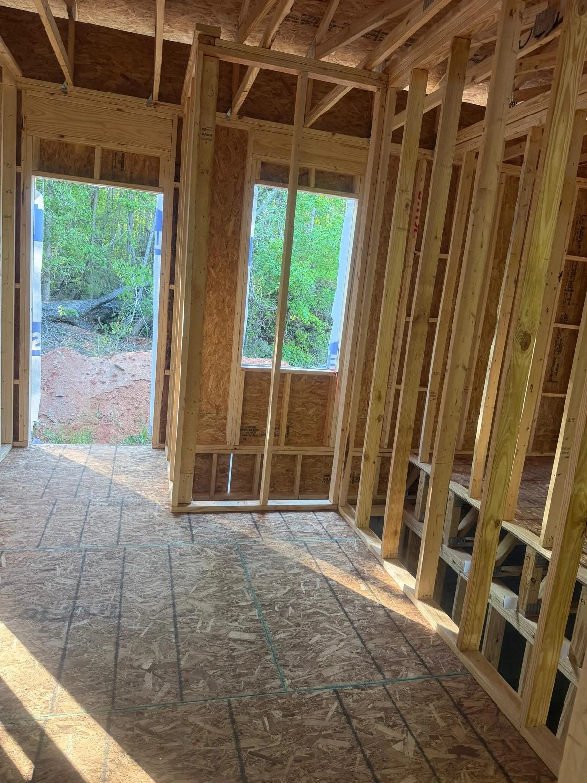 Interior framing with wooden studs, OSB sheathing, and installed double-hung windows