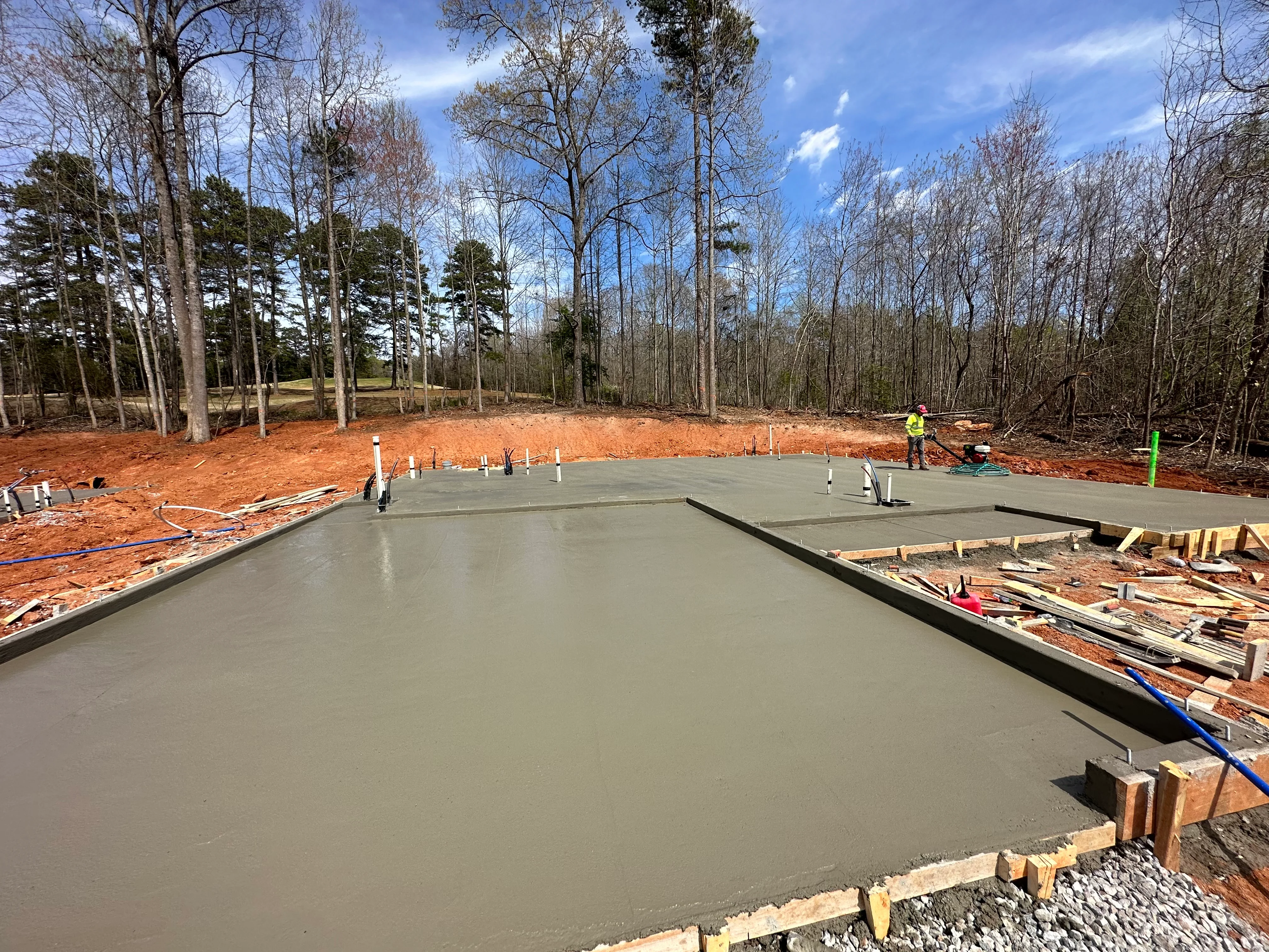 Freshly poured concrete foundation slab with wooden forms and site grading in progress