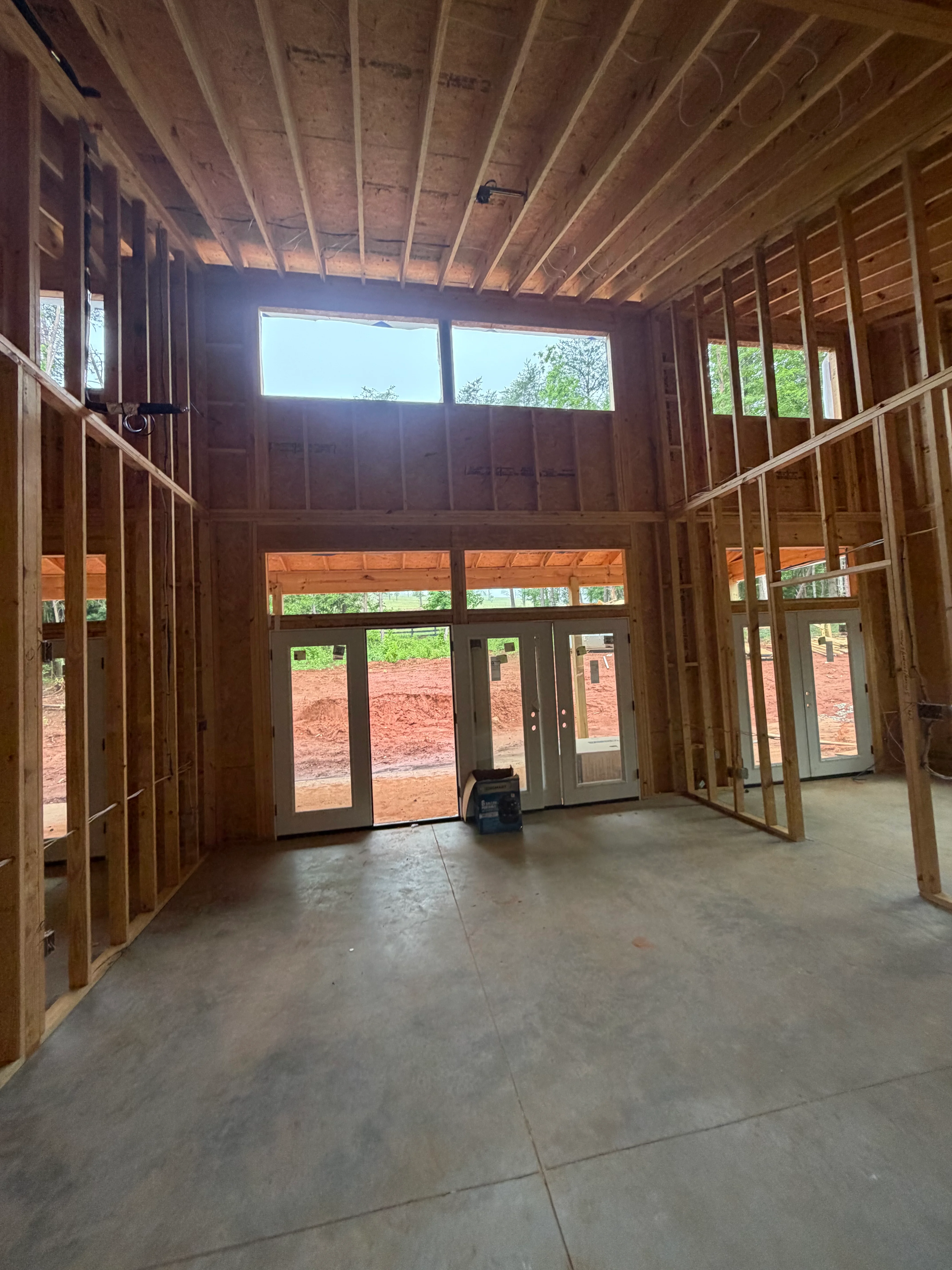Interior framing with wood studs, exposed ceiling joists, and aluminum-framed glass doors and windows