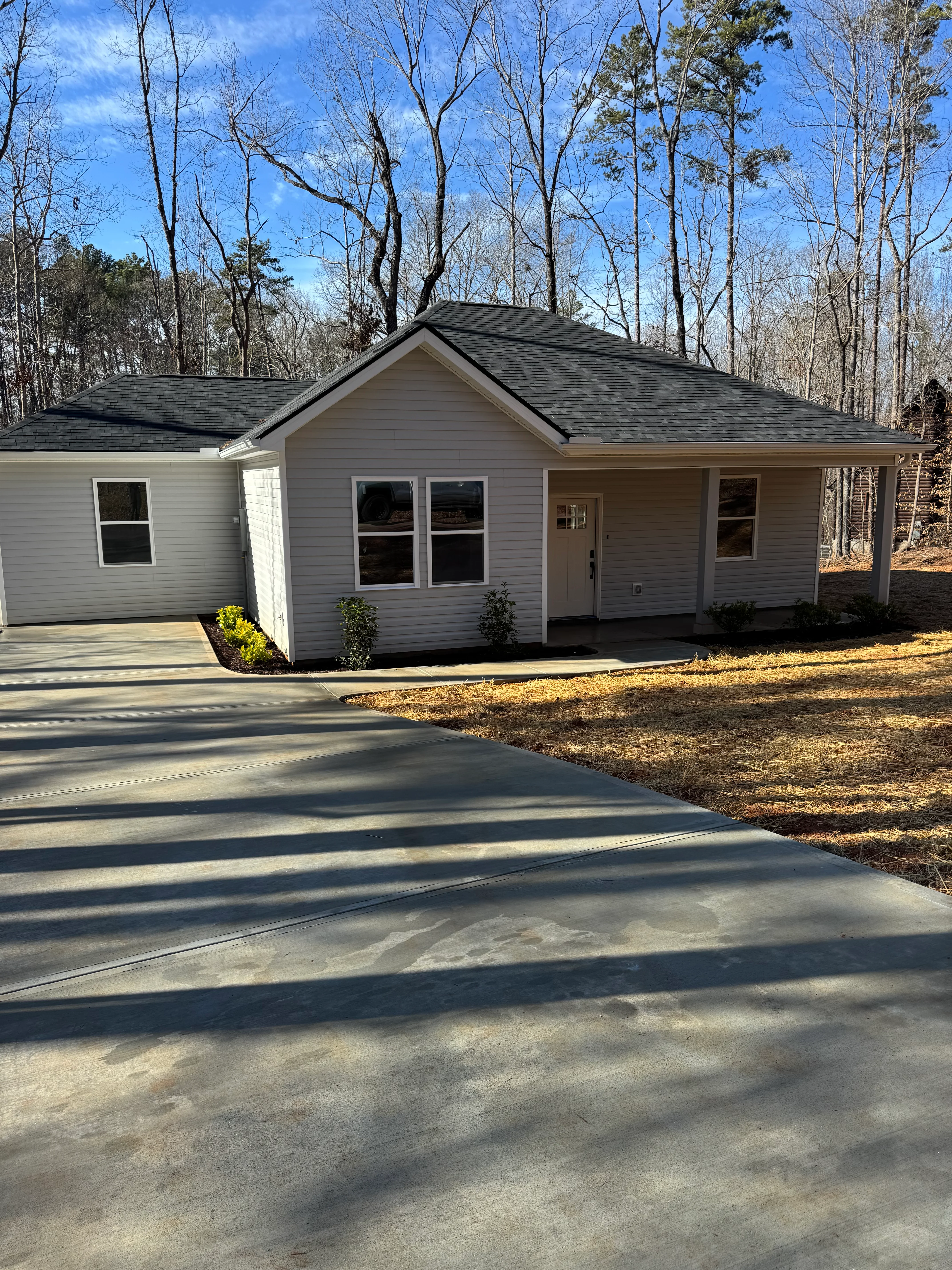 New charcoal gray architectural shingle roof on single-story home with gable design and white trim