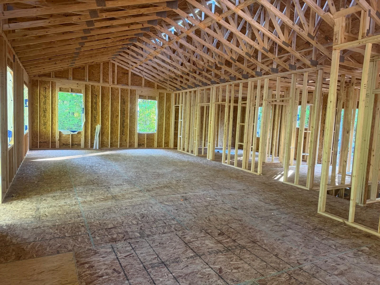 Interior view of new home framing with wooden trusses, collar ties, and OSB roof decking