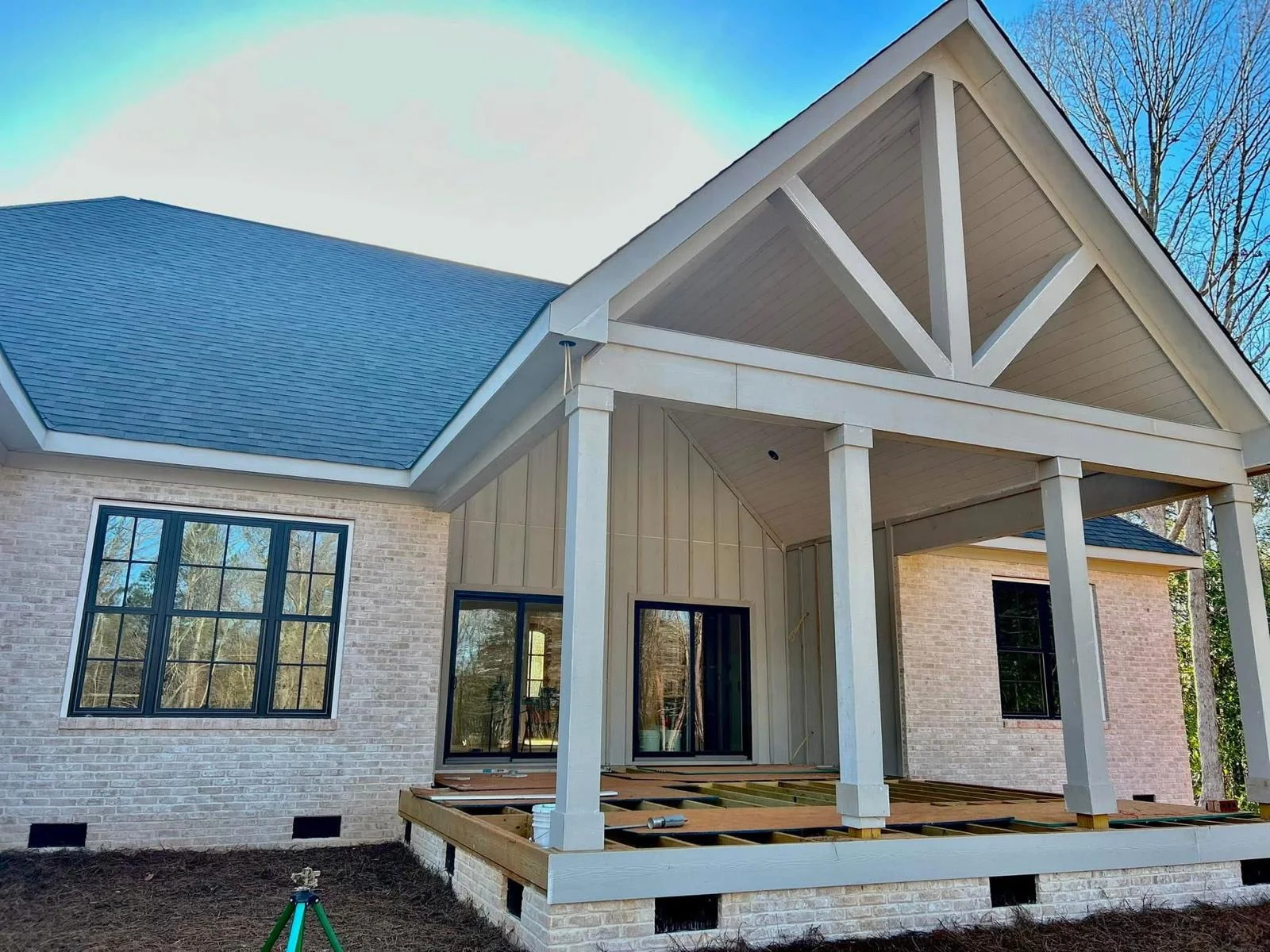 Standing seam metal roof installation on brick home with white porch columns and gable detailing