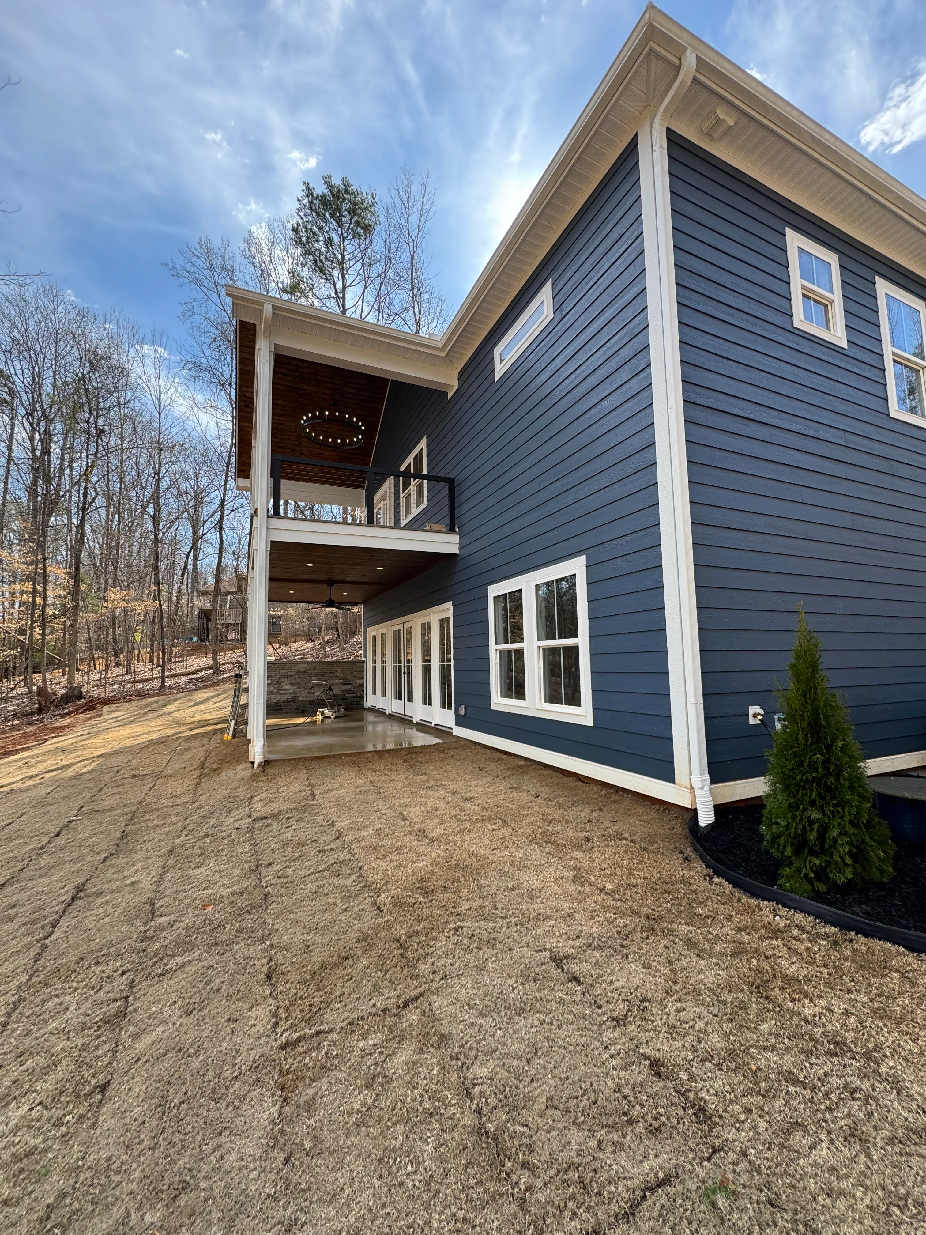 Dark blue board and batten siding with white trim on two-story home with covered deck and patio
