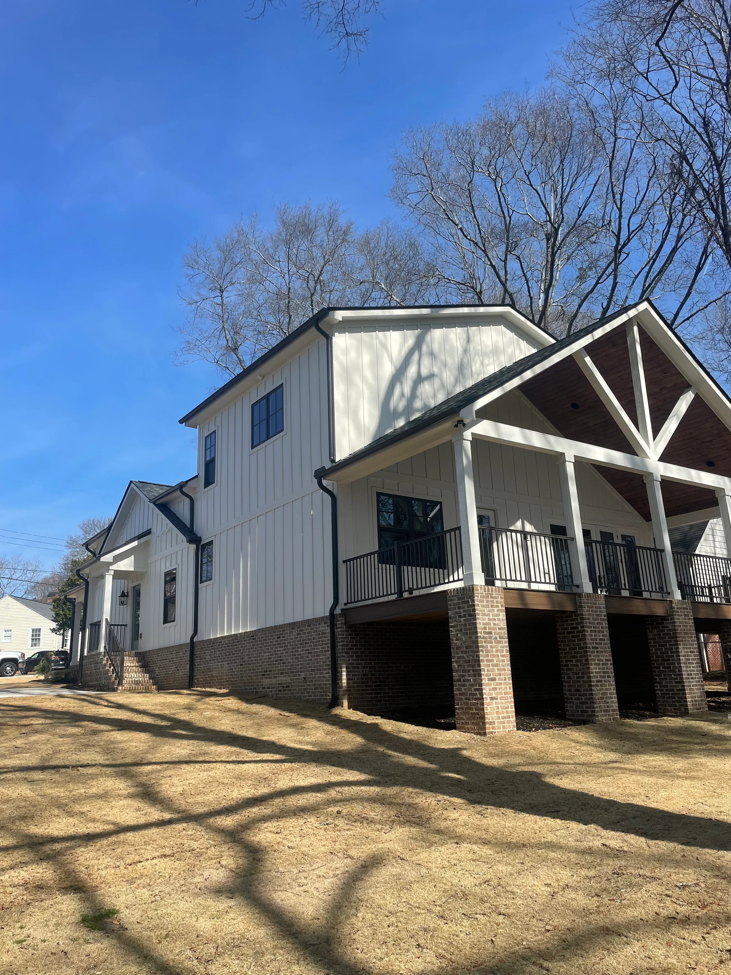 Standing seam metal roof on modern farmhouse with vertical siding and brick foundation