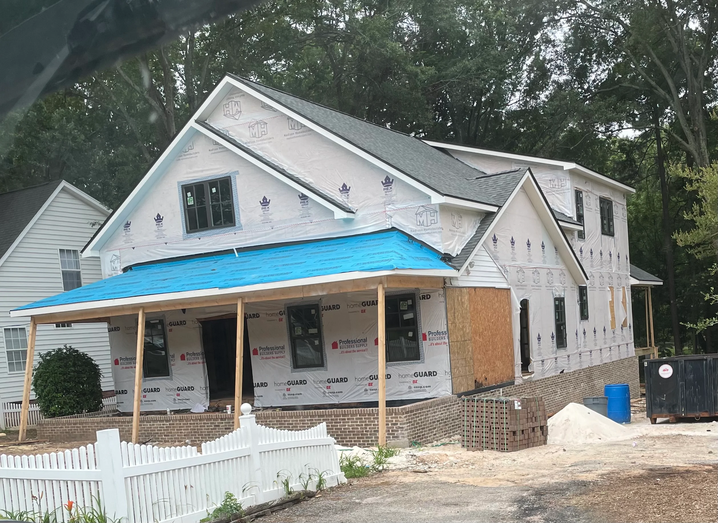 New home construction with gray architectural shingle roof installation and weather barrier wrap