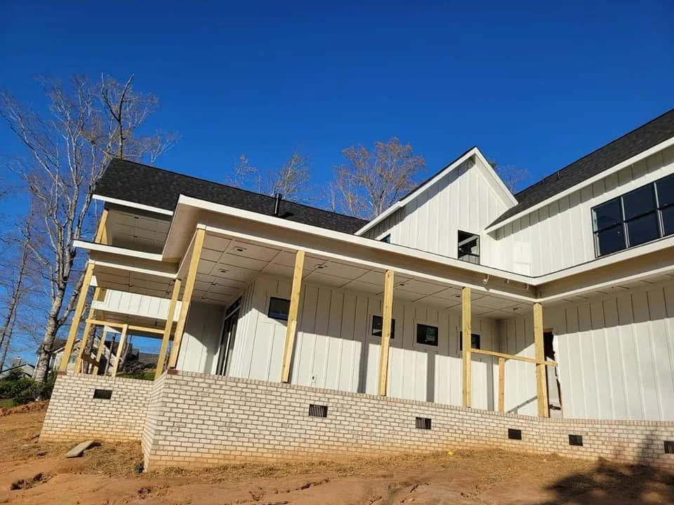 Metal roof and white metal siding on new farmhouse construction with brick foundation