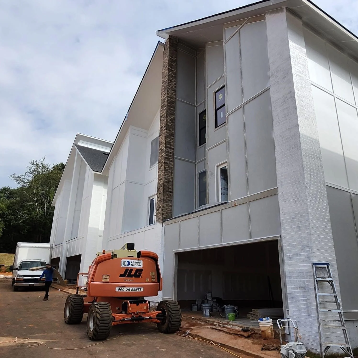 Light gray fiber cement siding with brick chimney, multi-story residential exterior under construction