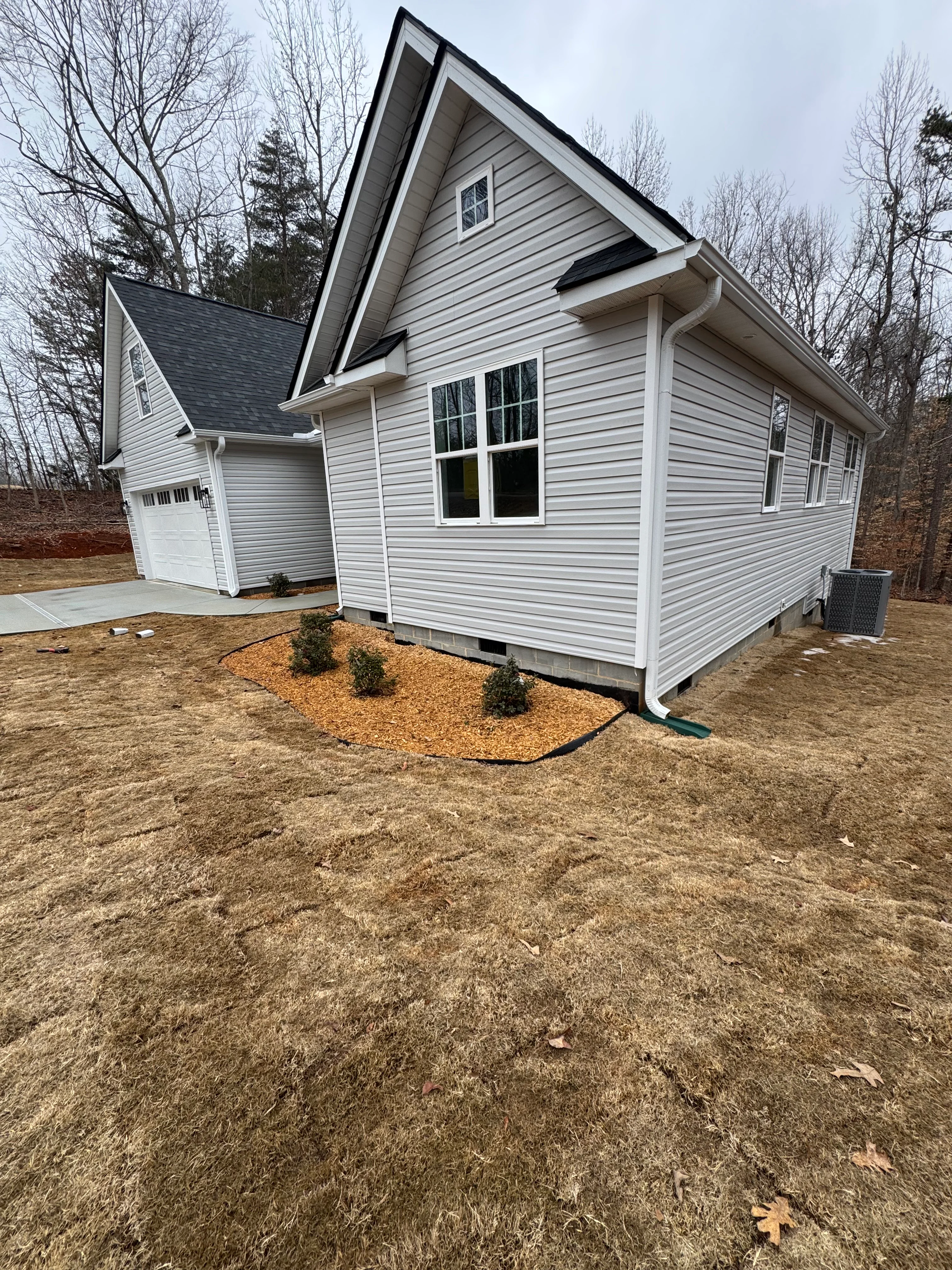 New home with dark gabled roof, white vinyl siding, and architectural shingle roofing installation